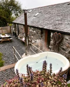 a bath tub in front of a stone house at Romantic Snowdonia Cottage with Hot tub, sea & mountain views in Tywyn