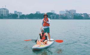 un homme et un enfant sur une planche de paddle dans l'eau dans l'établissement Luxury econest - Apartment with swimming pool & gym, à Hanoï