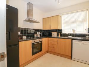 Una cocina con gabinetes de madera y un refrigerador negro. en The Hideaway, en Southsea