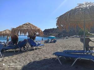 un grupo de sillas y sombrillas en una playa en achlia beach aparments 3, en Ierápetra