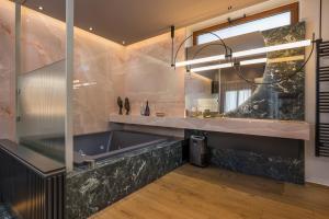 een badkamer met een groot bad en een grote spiegel bij Agave Suites in Chania