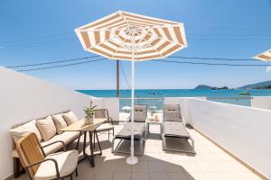 een patio met een tafel en stoelen en een parasol bij Mouria Studios & Apartments in Laganas