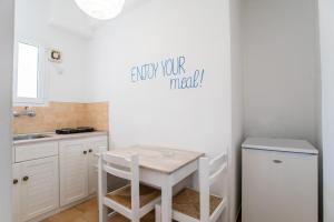 a white kitchen with a table and a sink at Livadia Seaside Studios 14 in Parikia