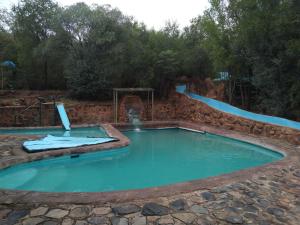 a large swimming pool with a slide in the middle at umbabala bush camp in Rustenburg