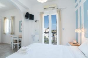 a white bedroom with a bed and a balcony at Livadia Seaside Studios 12 in Parikia