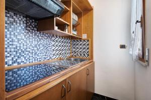 a kitchen with a sink and a blue tiled wall at Residence Paradiso Bilocale 303 in Moneglia