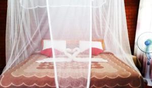 a bed with white curtains and red pillows at Rokkyhill in Ella