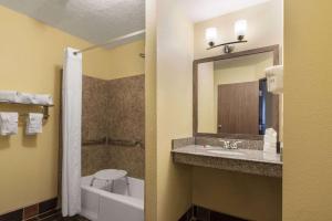 a bathroom with a sink and a toilet and a mirror at Days Inn by Wyndham Tucumcari in Tucumcari