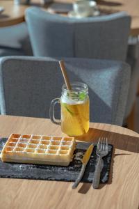 Un gofre, un tarro de miel y una bebida en una mesa. en Hôtel Le Rivage vue sur mer - Châtelaillon-plage, en Châtelaillon-Plage