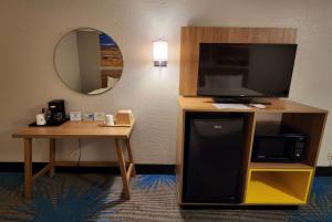 a hotel room with a television and a desk with a table at Days Inn by Wyndham Tucumcari in Tucumcari