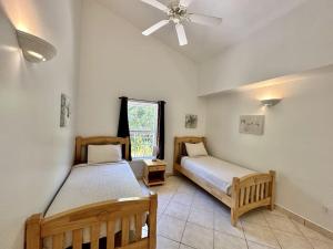 a bedroom with two beds and a ceiling fan at Villa Utopia in Jolly Harbour