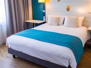 a hotel room with a large bed with blue and white sheets at Mercure Lorient Centre in Lorient