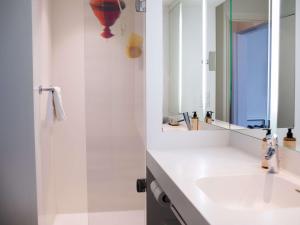 a white bathroom with a sink and a mirror at Mercure Lorient Centre in Lorient