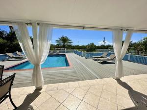 a pool with white curtains and chairs next to a swimming pool at Villa Utopia in Jolly Harbour