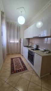 una cocina con armarios blancos y una alfombra en el suelo en Summer Home, en Vlorë