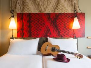 a guitar sitting on top of a bed at ibis Europe Chalon Sur Saone in Chalon-sur-Saône