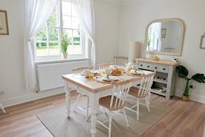 een witte eettafel met stoelen en een spiegel bij Secluded holiday cottage near the Wolds Way 