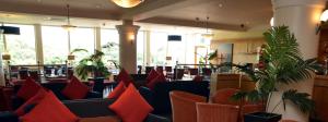 a restaurant with red pillows on couches and plants at The Riviera Hotel & Apartments - Alum Chine in Bournemouth