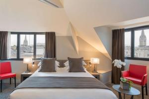 a hotel room with a bed and two red chairs at Best Western Plus Le Moderne in Caen