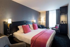 um quarto de hotel com uma cama grande e almofadas cor-de-rosa em Best Western Plus Le Moderne em Caen