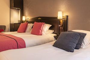 two beds in a hotel room with red and white pillows at Best Western Plus Le Moderne in Caen