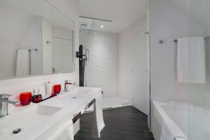 - une salle de bains blanche avec deux lavabos et une douche dans l'établissement Best Western Plus Le Moderne, à Caen