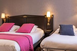 two beds in a hotel room with pink and blue pillows at Best Western Plus Le Moderne in Caen