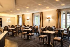 a restaurant with tables and chairs in a room at Best Western Plus Le Moderne in Caen
