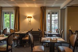 a dining room with tables and chairs and windows at Best Western Plus Le Moderne in Caen