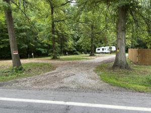 a road in a park with a rv parked next to trees at Prairie House RV Spaces in Deerfield