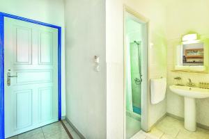 uma casa de banho com um chuveiro, um lavatório e uma porta em Xenios Faros Apartments em Possidi