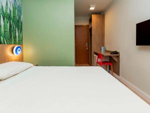 Schlafzimmer mit einem großen weißen Bett und einem Schreibtisch in der Unterkunft ibis Styles Araraquara in Araraquara