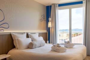 two stuffed animals sitting on top of a bed with a window at Best Western Hotel Matisse in Sainte-Maxime