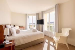 a white bedroom with a large bed and a chair at Best Western Hotel Matisse in Sainte-Maxime
