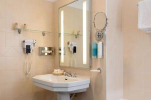 a bathroom with a sink and a mirror and a phone at Best Western Hotel Matisse in Sainte-Maxime