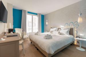 a bedroom with a bed with a desk and a tv at Best Western Hotel Matisse in Sainte-Maxime