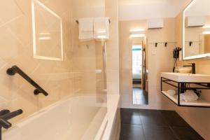 a bathroom with a bath tub and a sink at Best Western Hotel Matisse in Sainte-Maxime