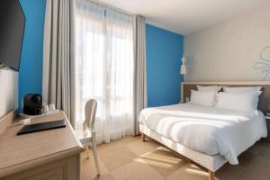 a bedroom with a bed and a desk with a laptop at Best Western Hotel Matisse in Sainte-Maxime