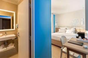a hotel room with a bed and a desk and a bathroom at Best Western Hotel Matisse in Sainte-Maxime
