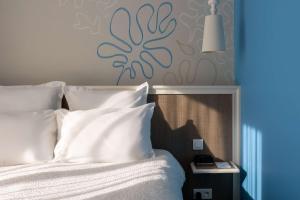 a bed with white pillows and a blue wall at Best Western Hotel Matisse in Sainte-Maxime