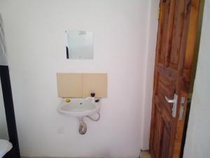 a bathroom with a sink in a white wall at MUNDO GUEST & STUDIO APARTMENTS, MTWAPA,mombasa in Mtwapa