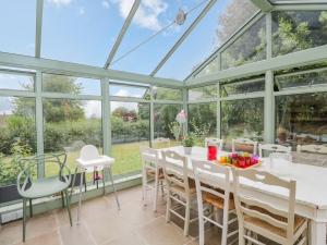 a conservatory with a table and chairs and windows at 9 Velley Hill in Corsham