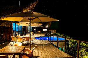 a deck with tables and umbrellas and a swimming pool at Massinga Beach in Massinga