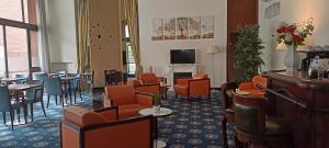 - une salle d'attente avec des tables, des chaises et une télévision dans l'établissement iH Hotels Milano Eur - Trezzano sul Naviglio, à Trezzano sul Naviglio