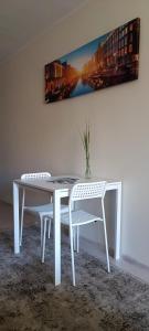 une table blanche et deux chaises dans une pièce dans l'établissement Apartamentai PAlanga, à Palanga