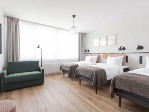 ein Hotelzimmer mit 2 Betten und einem grünen Stuhl in der Unterkunft Oru Hub Hotel Tallinn - Handwritten Collection in Tallinn