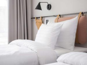 a bed with white pillows and a lamp on it at Oru Hub Hotel Tallinn - Handwritten Collection in Tallinn