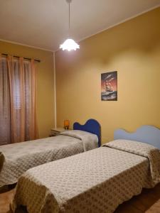 two beds in a room with yellow walls at Casa in Centro in SantʼAntìoco
