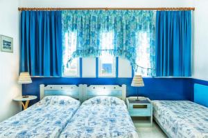 Duas camas num quarto com paredes e janelas azuis em Xenios Faros Apartments em Possidi