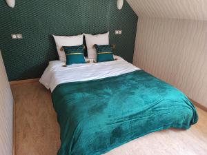 a bedroom with a large bed with green sheets and pillows at la madeleine in Saint-Benoît-sur-Loire